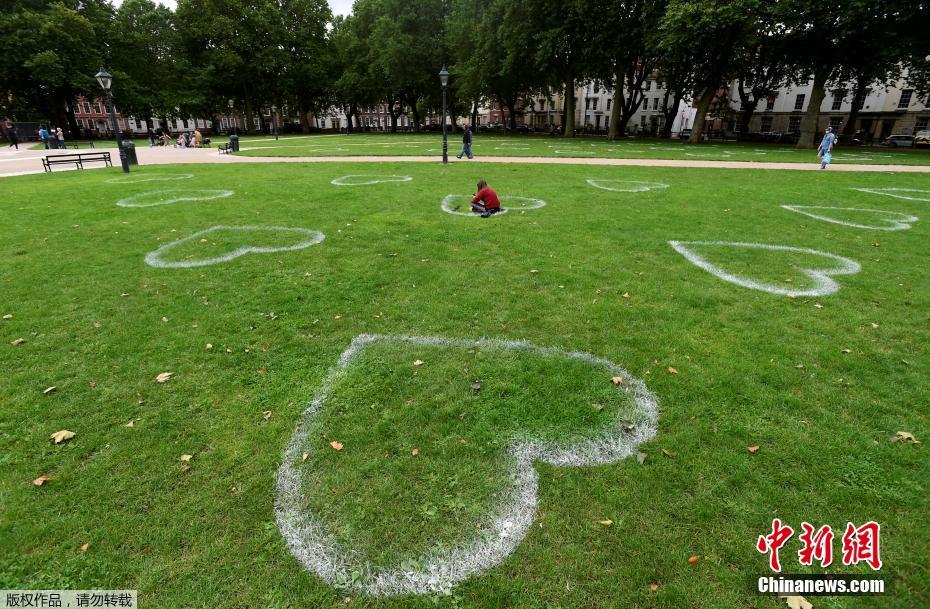 英国艺术家草地上画心敦促保持距离 变成浪漫约会地