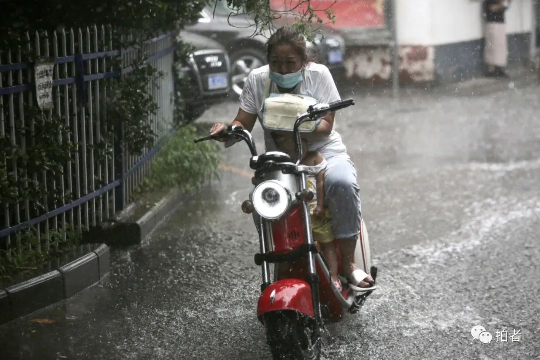  △ 上午，复兴路，市民冒雨骑车并为孩子遮雨。摄影/新京报记者郑新洽