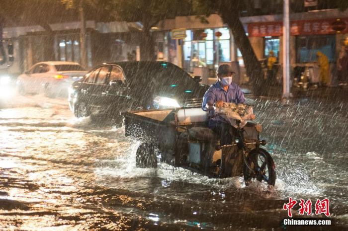 资料图：8月9日晚，北京市民冒雨涉水出行。当日，北京气象台发布18时至23时降水量(毫米)：全市平均17.9，城区平均28.1。大部地区出现7、8级阵风，局地达9到11级。 中新社记者 田雨昊 摄