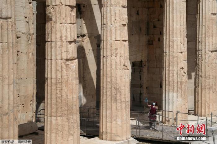 资料图：一名戴口罩的游客在参观希腊雅典卫城。