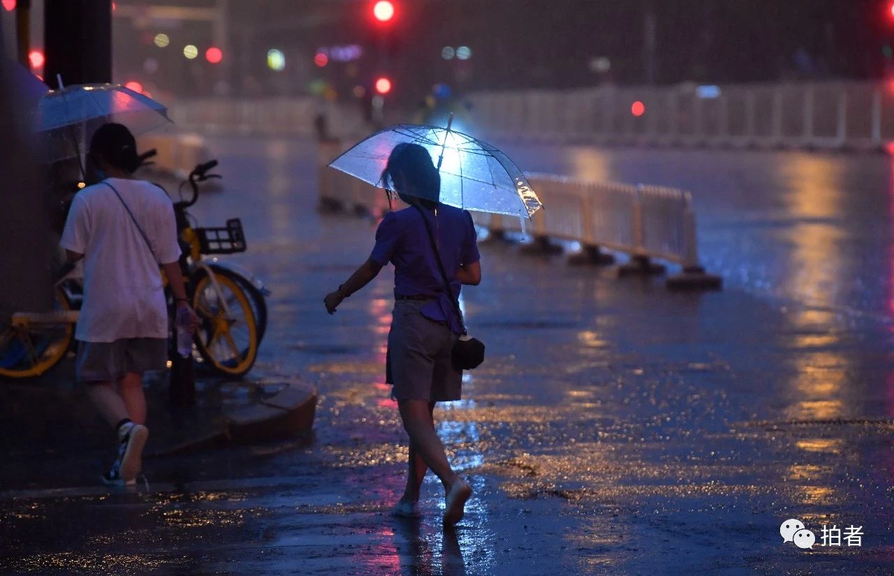 △ 东四十条桥西公交站附近，市民走在雨中。摄影/新京报记者李木易