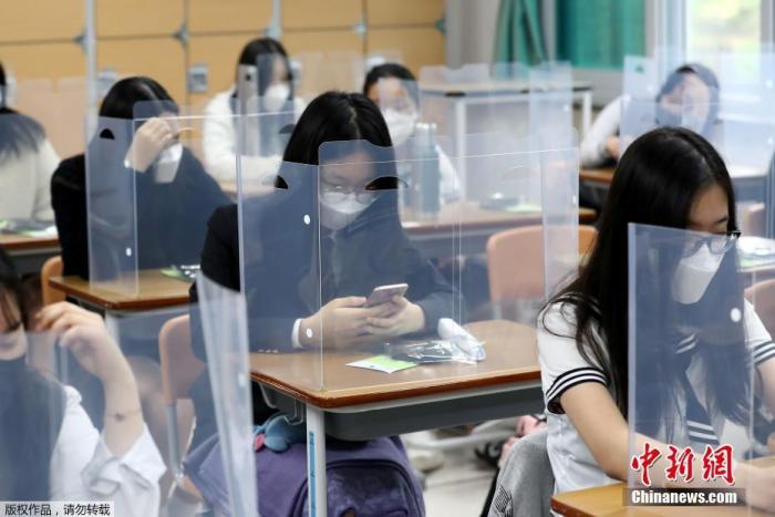 资料图：当地时间5月20日，韩国高三学生复课，韩国大田一所学校的课桌上安装了塑料挡板以防止病毒传播。