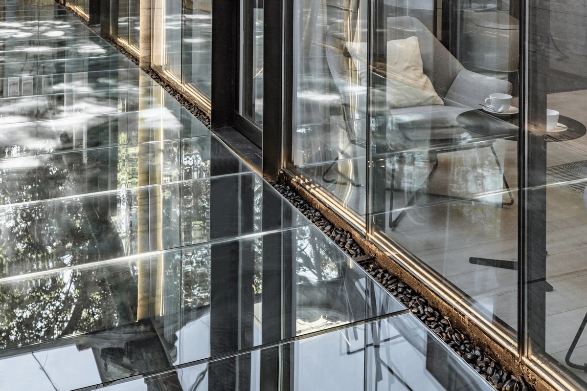 镜面地面映射出周围环境,建筑被树木,天空所包围,仿佛消失在环境之中