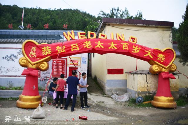 一条狭窄的胡同口,也立起了气拱门,上面写着"恭贺吕老太太百岁大寿"