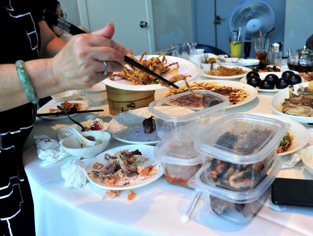 徐汇滨江的一家饭店里,一位女士正在将餐宴后没吃完的菜肴一一装盒