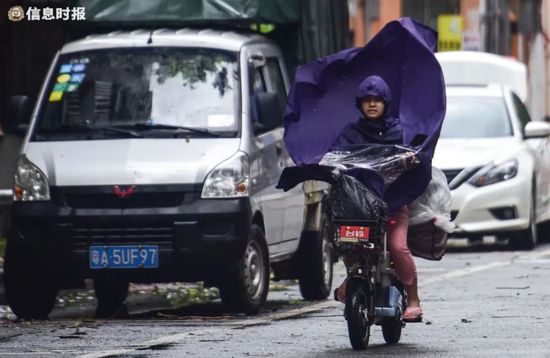 番禺区富华西路,一位骑车市民的雨衣被大风吹起.