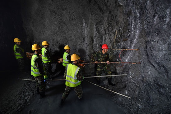 沙子呷(右一)带领官兵在爆破作业面装填炸药.刘明松/摄