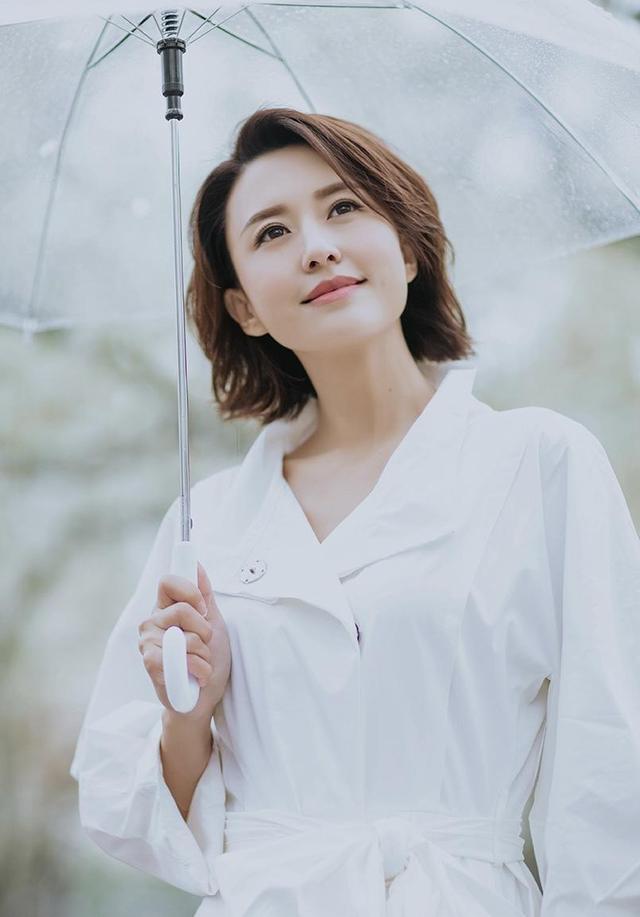 张蕾雨中漫步太迷人,穿白色连衣裙配小白鞋,撑伞一笑高级又养眼
