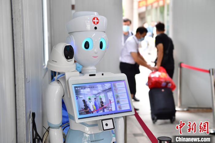 人工智能机器人正在对进入院区的患者和家属测量体温,高效的操作避免