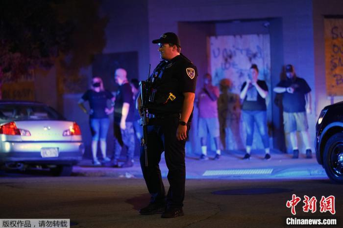 当地时间2020年8月25日，美国威斯康星州基诺沙，一名警察站在抗议者聚集的街道上。