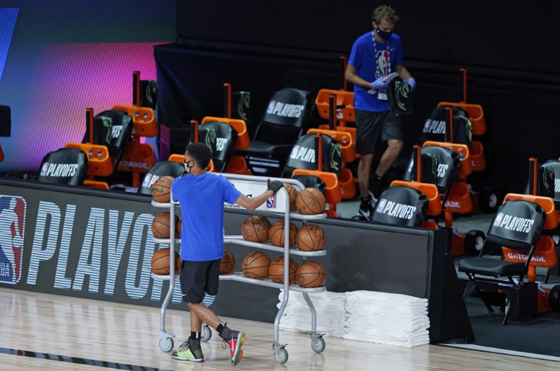 比赛暂停，现场工作人员在清理篮球等物品。