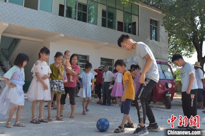 志愿者和小学生一起踢球。　肖亚辉 摄