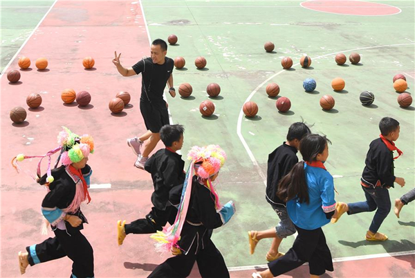 9月8日,谌业权(上)在广西百色市凌云县泗城镇览金小学给学生们上篮球