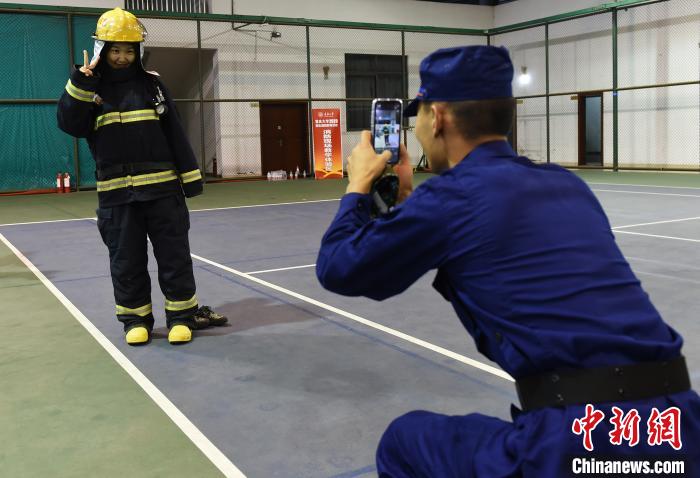 图为教官为试穿消防防护服的大学生拍照留念。　　周毅 摄