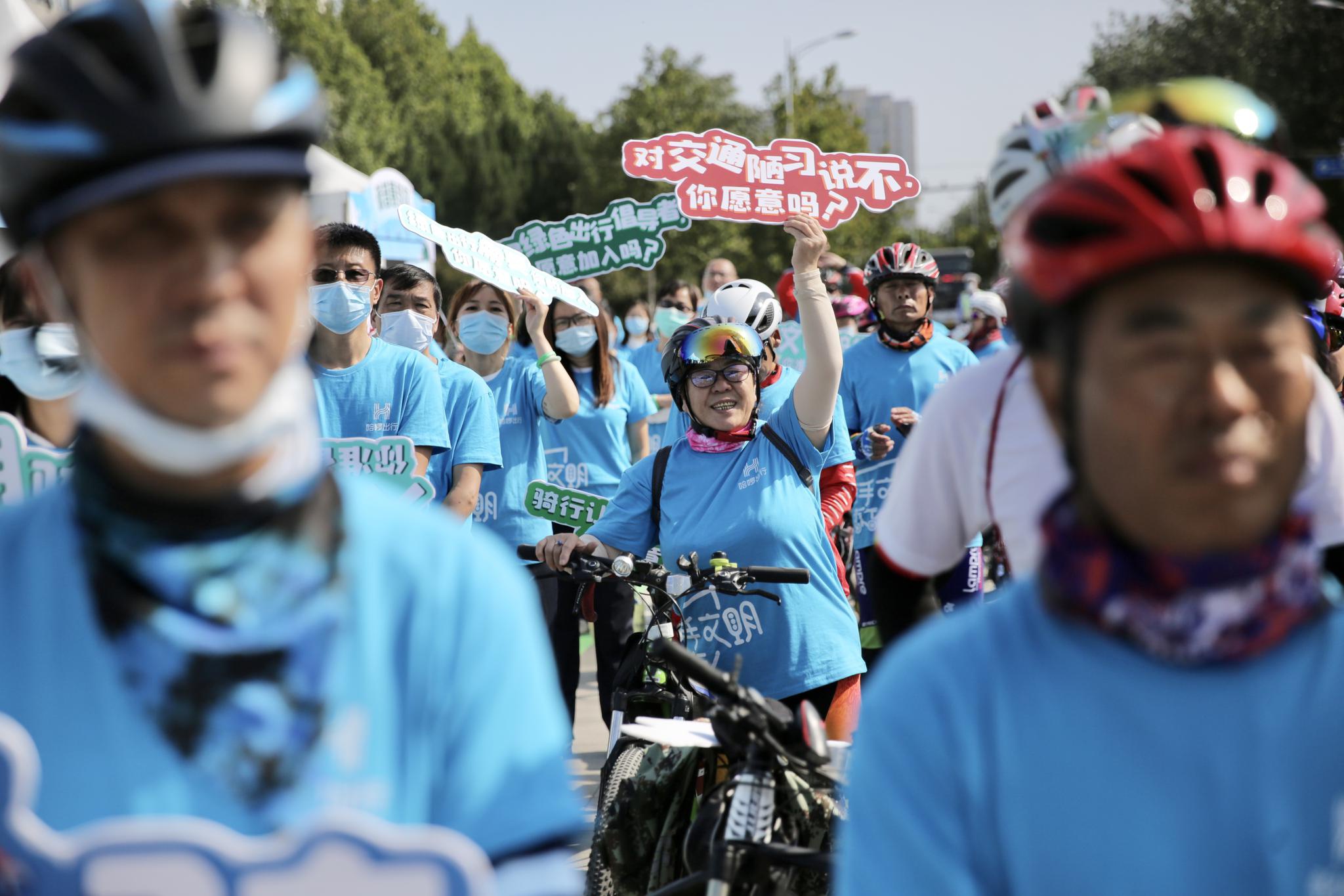 参加活动的骑行爱好者手举绿色出行标语。新京报记者 郑新洽 摄