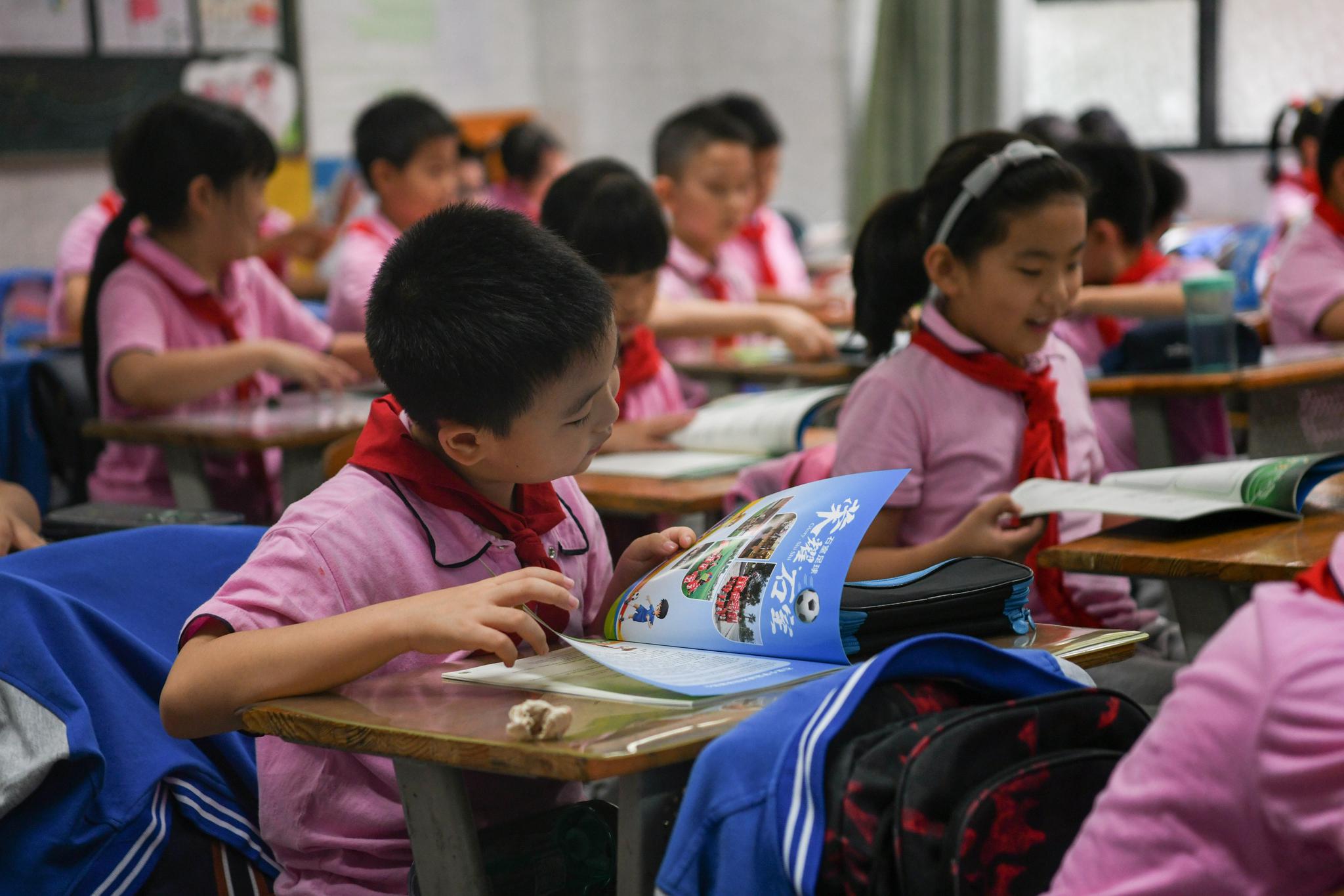 在成都石室小学,学生在足球理论课上翻看校园足球体验手册(9月22日摄)