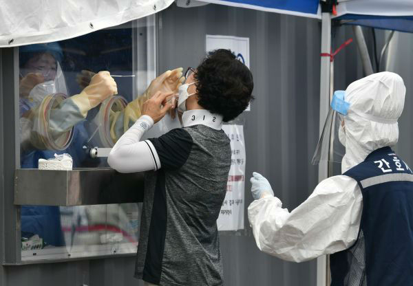 8月26日， 一名女子在韩国首尔一处检测站接受新冠病毒检测取样。新华社/法新