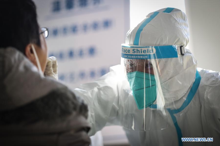 A medical worker collects a swab sample from a resident at a coronavirus testing site in Tiexi District of Shenyang, northeast China's Liaoning Province, Jan. 1, 2021. Shenyang is conducting nucleic acid tests for all residents in nine districts starting Thursday, local authorities said. The extensive testing drive covering most urban areas is aimed at screening coronavirus infections. (Xinhua/Pan Yulong)