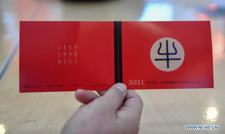 A stamp collector shows the cover of the newly issued special stamps themed on the Year of the Ox in Changchun, northeast China's Jilin Province, Jan. 5, 2021. China Post on Tuesday issued a set of two special stamps to mark the upcoming Year of the Ox. (Xinhua/Zhang Nan)