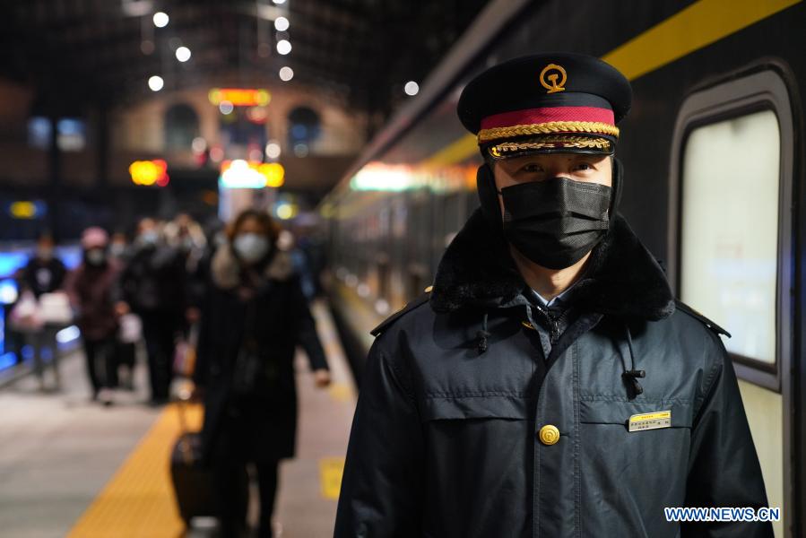 A staff member guides passengers outside train K7093 heading for Hailar, north China's Inner Mongolia Autonomous Region, at Harbin Railway Station in Harbin, northeast China's Heilongjiang Province, Jan. 6, 2021. Train No. K7093/4, connecting Harbin and Hailar, runs a distance of 1,320 kilometers and stops at 52 stations during the about 26-hour trip. The train stops every 30 minutes on average due to so many stops and is known as the slowest train in the forest area between the two destinations. Having operated for over 30 years, the train's facilities have witnessed upgrade and created a cozy environment for passengers. (Xinhua/Wang Jianwei)
