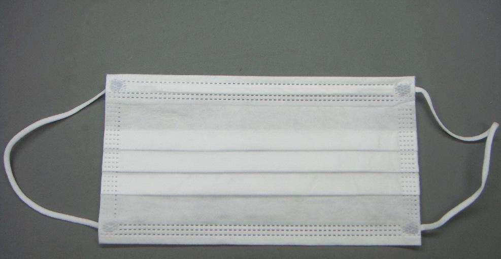 然后撕成细碎的小片,越碎越好,然后平铺在桌子上,将口罩的外侧贴近