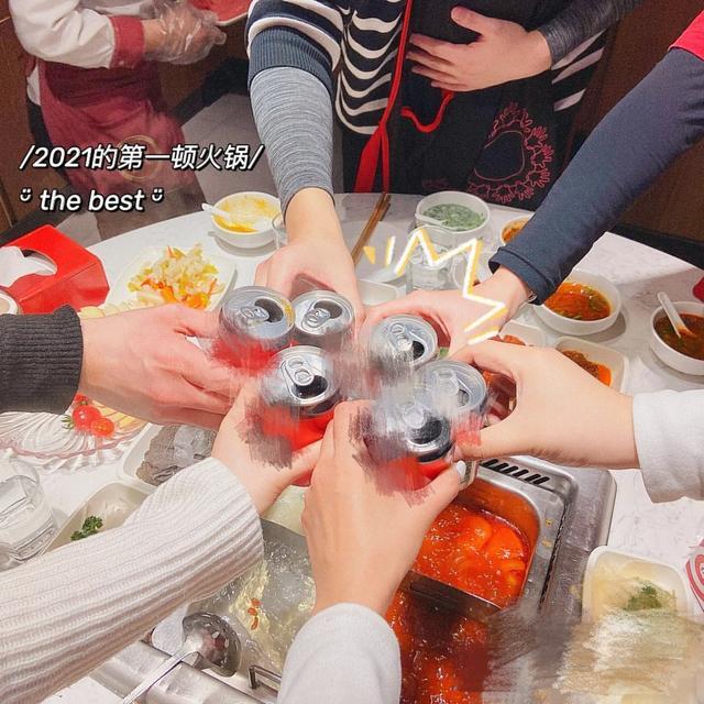 大家一起吃火锅的场景,只见众人围绕着摆满食材的桌子,站起来一起干杯