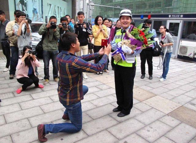 农村小伙街头跪地向女交警求婚,引来了记者围观群众