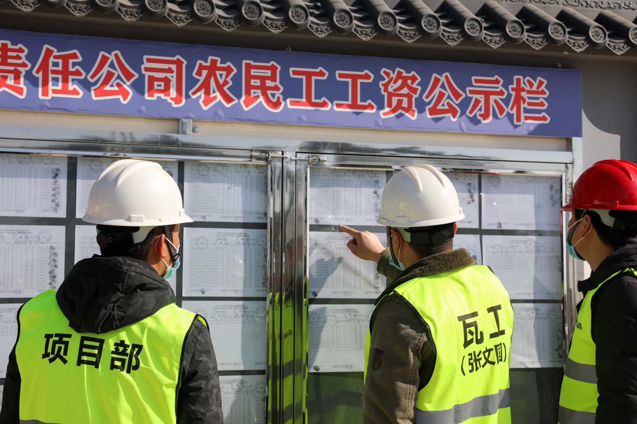 1月14日,滁州(安徽),农民工在公示栏核对考勤及工资发放情况.