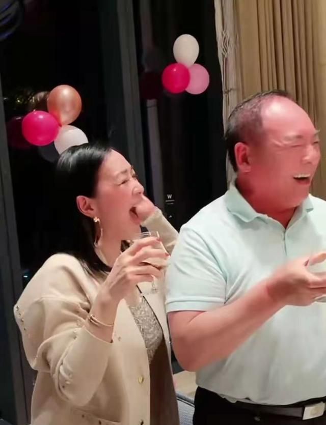 钟丽缇一边和公公梅尼耶碰杯一边又将手搭在公公的肩膀上