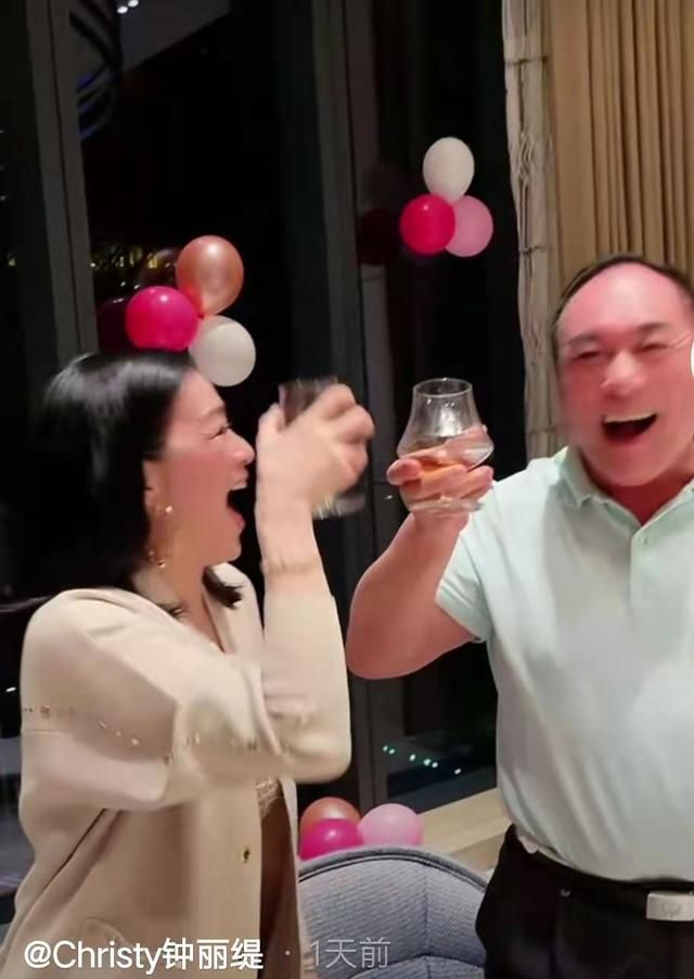 钟丽缇一边和公公梅尼耶碰杯一边又将手搭在公公的肩膀上