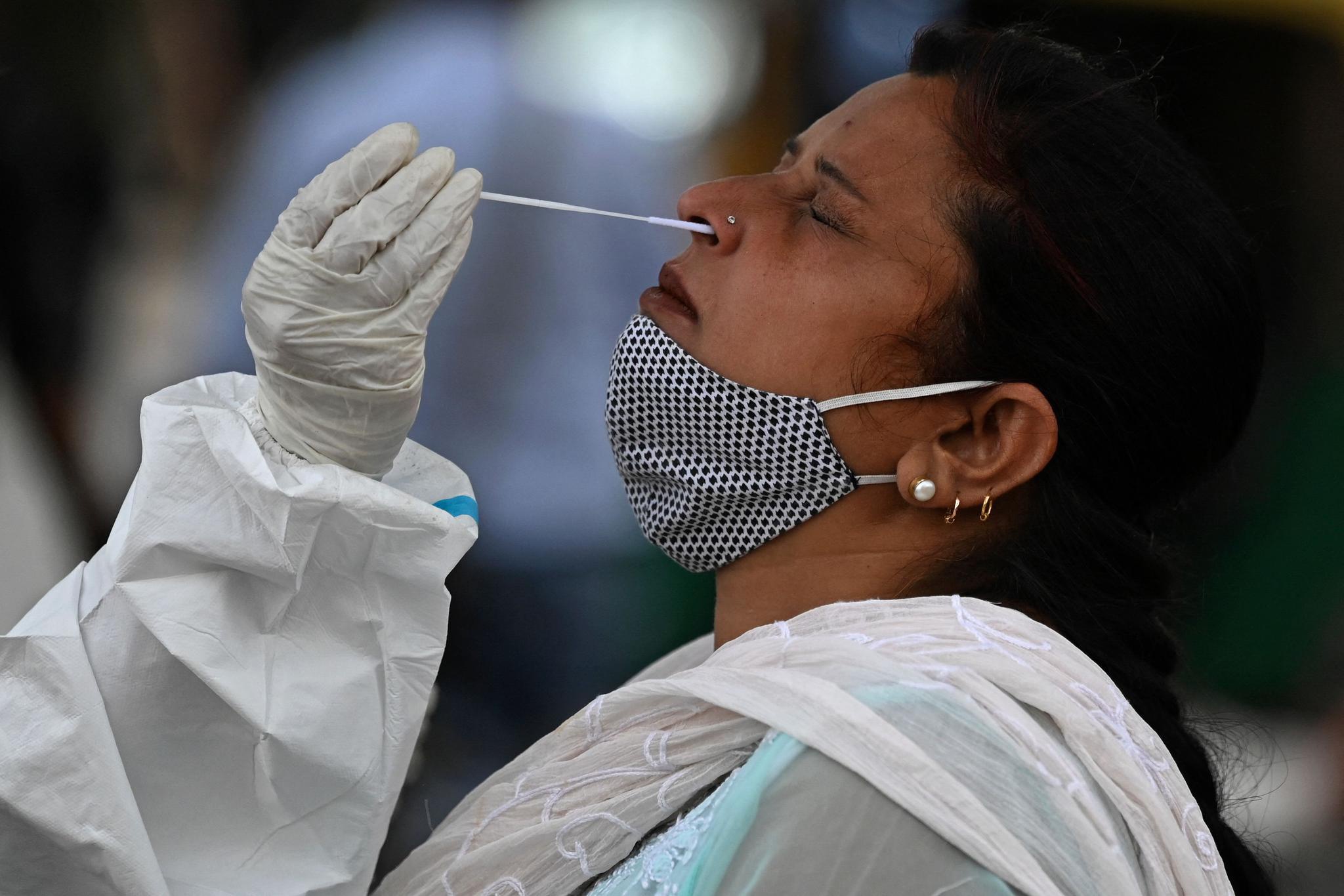 3月23日,医务人员在印度新德里为一名女子进行新冠病毒检测取样.