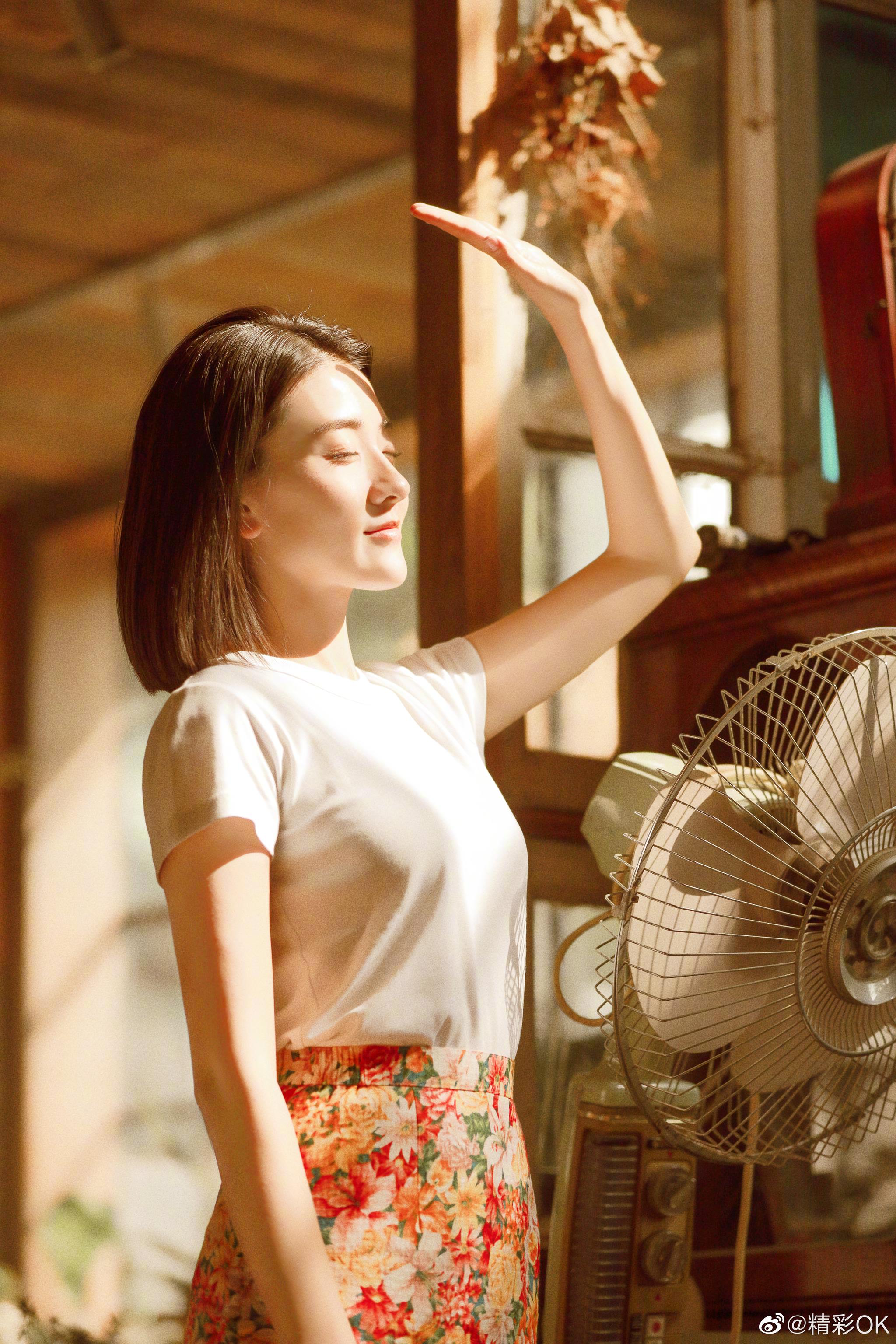 梁洁简约白t搭配俏皮碎花裙或坐在窗前小憩演绎浪漫怀旧风