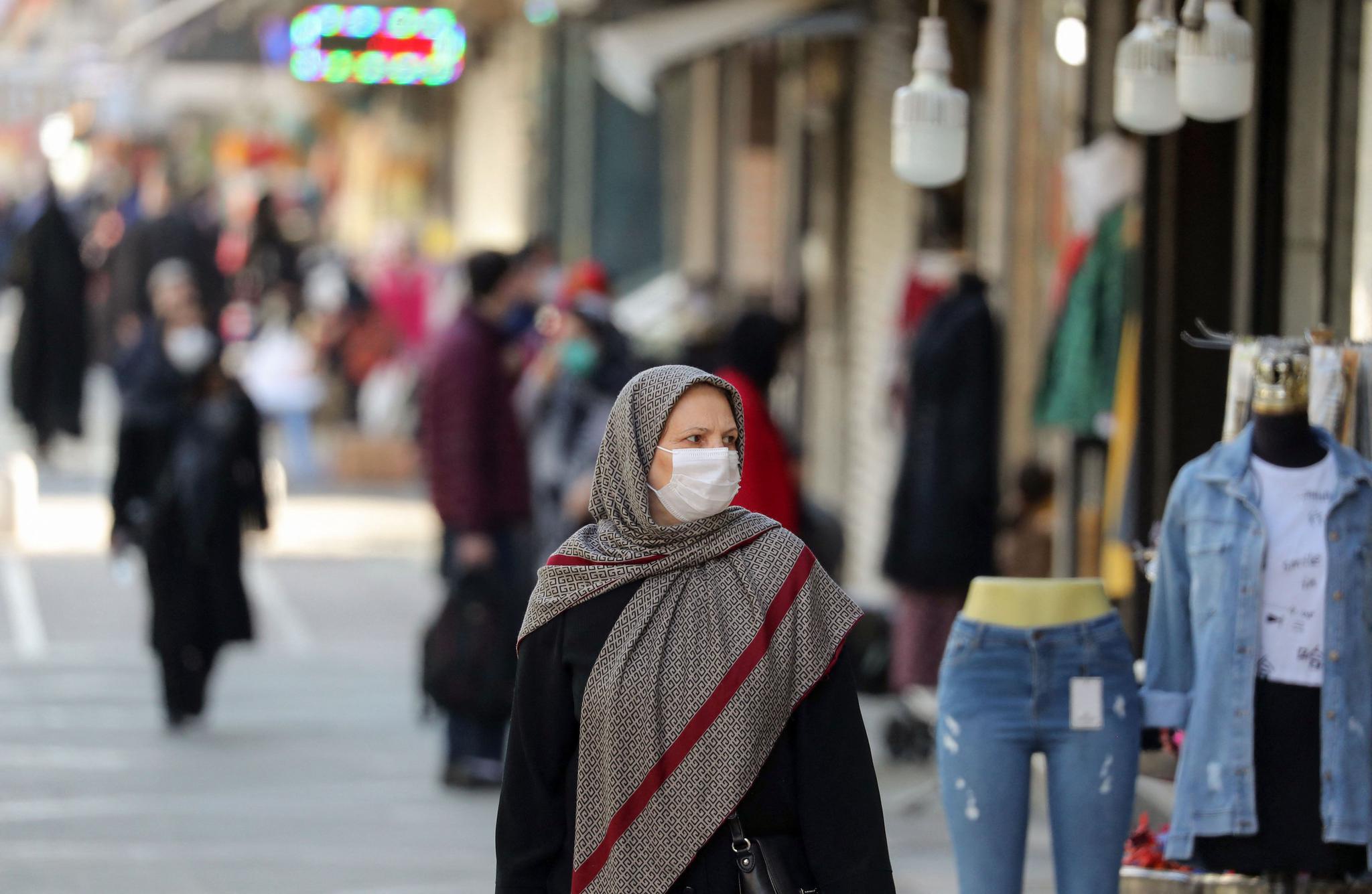 3月29日,一名女子戴着口罩走在伊朗德黑兰街头.
