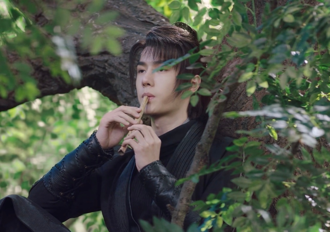 一袭黑衣坐在树上吹笛,恣意潇洒,王一博在《有翡》里饰演的谢允,吹笛