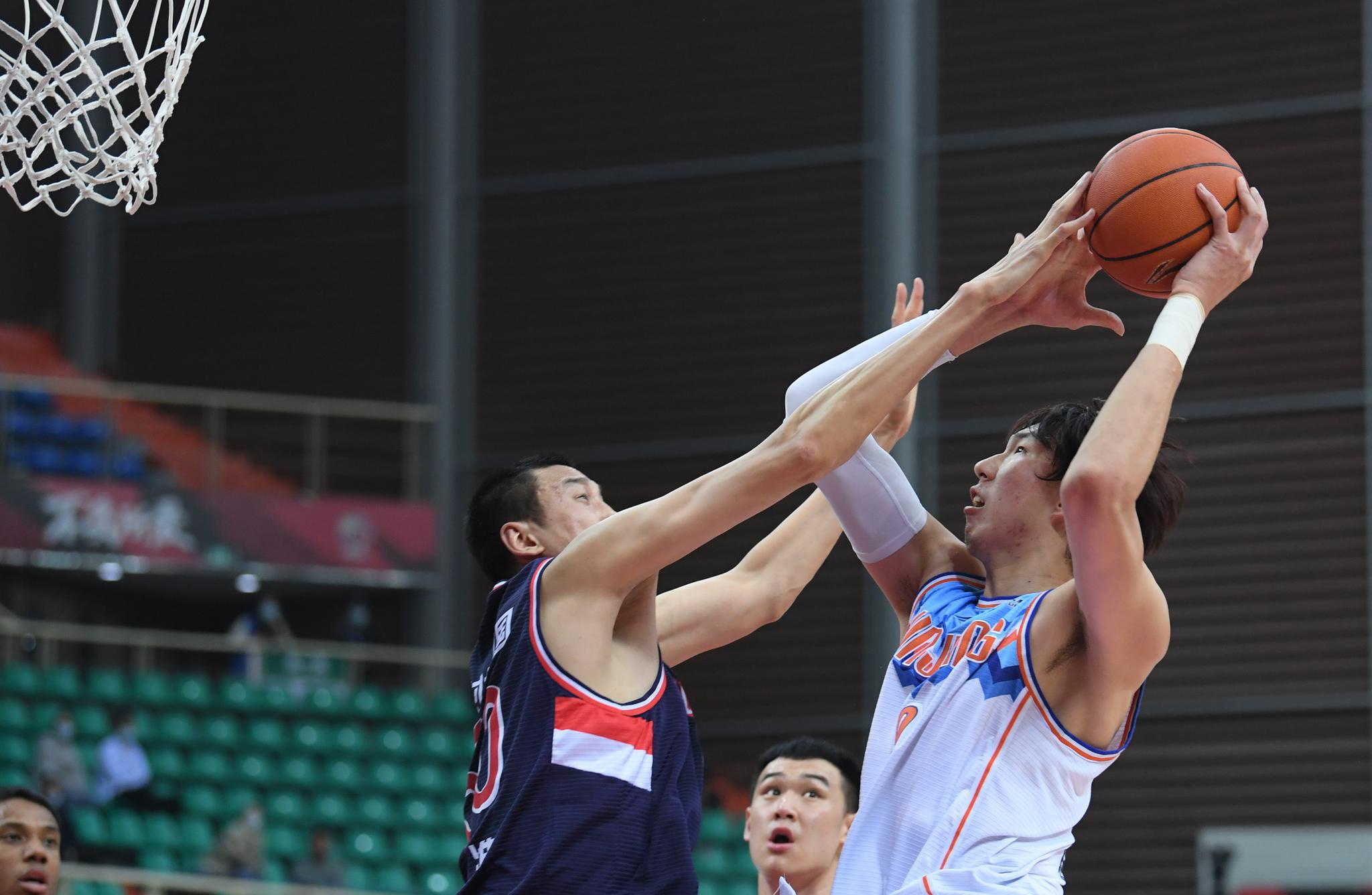 4月13日,新疆伊力特队球员周琦(右)在比赛中投篮.