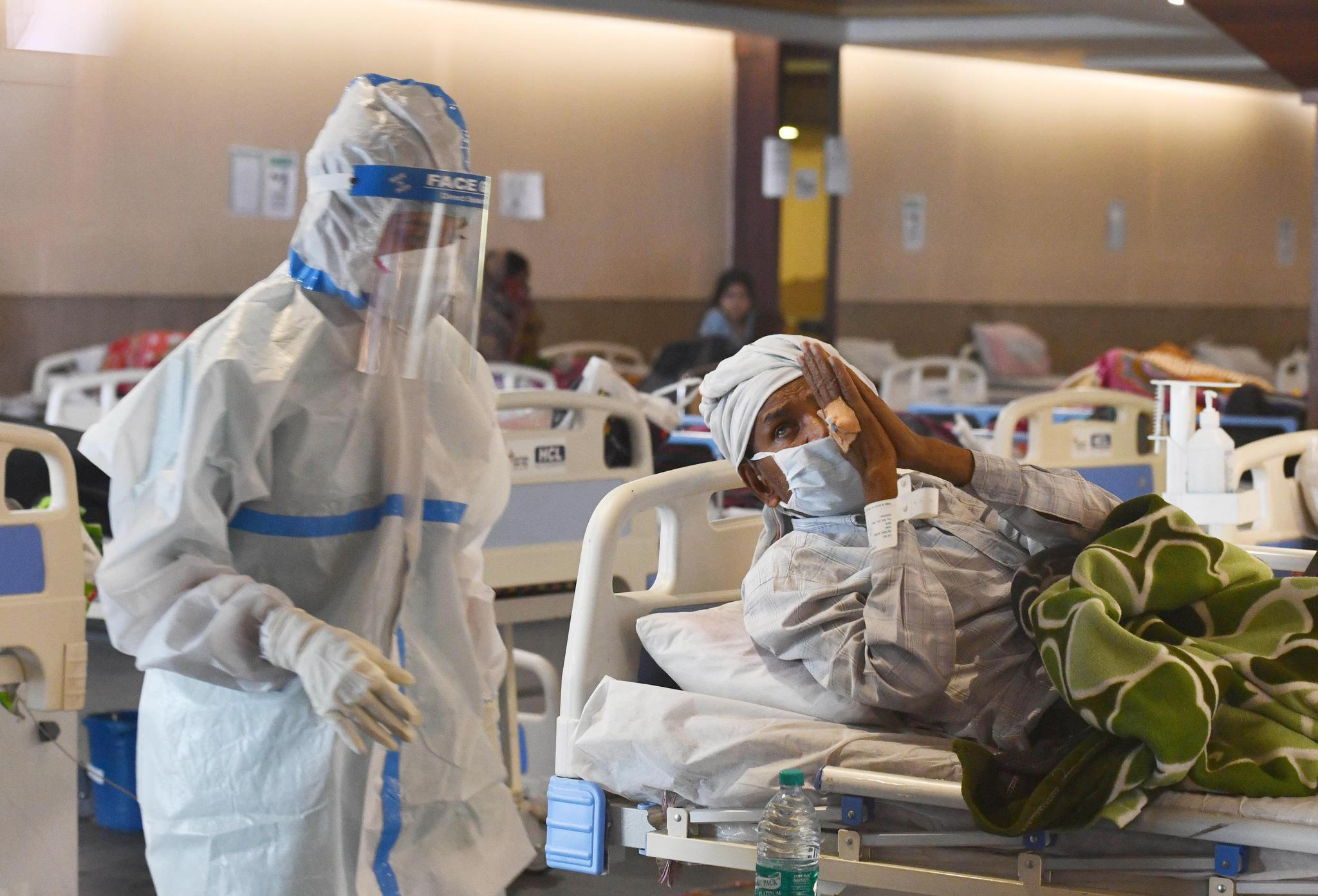 4月13日,医务人员身着防护服在印度首都新德里一家医院的隔离区照看新