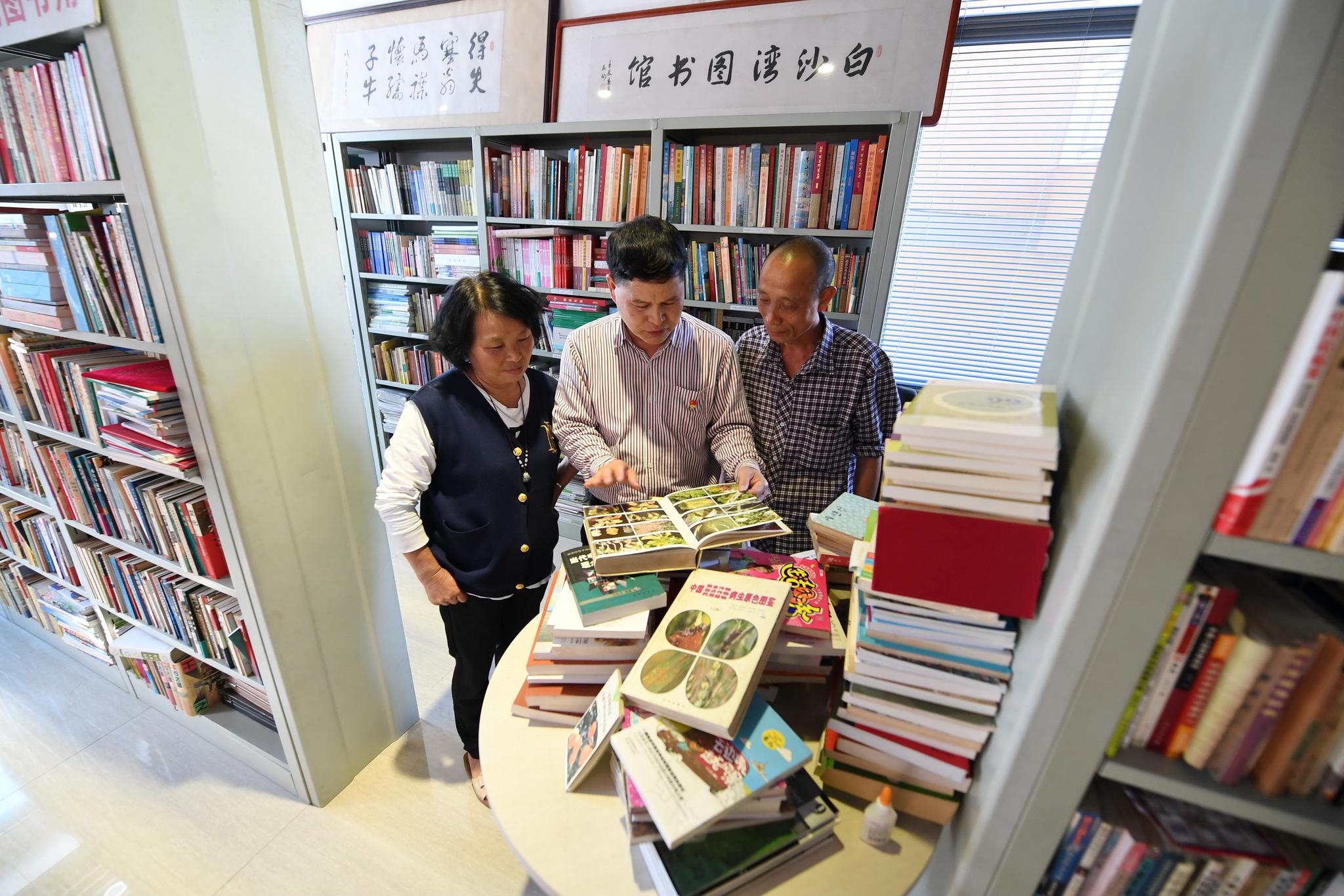 新华社记者 林善传 摄4月21日,林岳铿(中)在白沙湾图书馆和乡亲们一起