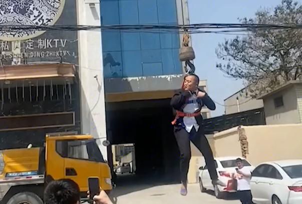 在河南郑州的街头,就出现了这样的一幕:西装革履的新郎,被人吊在半空