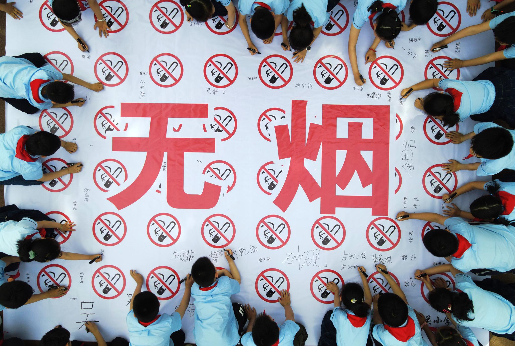 5月28日,江苏省扬州市东关小学的学生在宣传禁烟的横幅上签名.