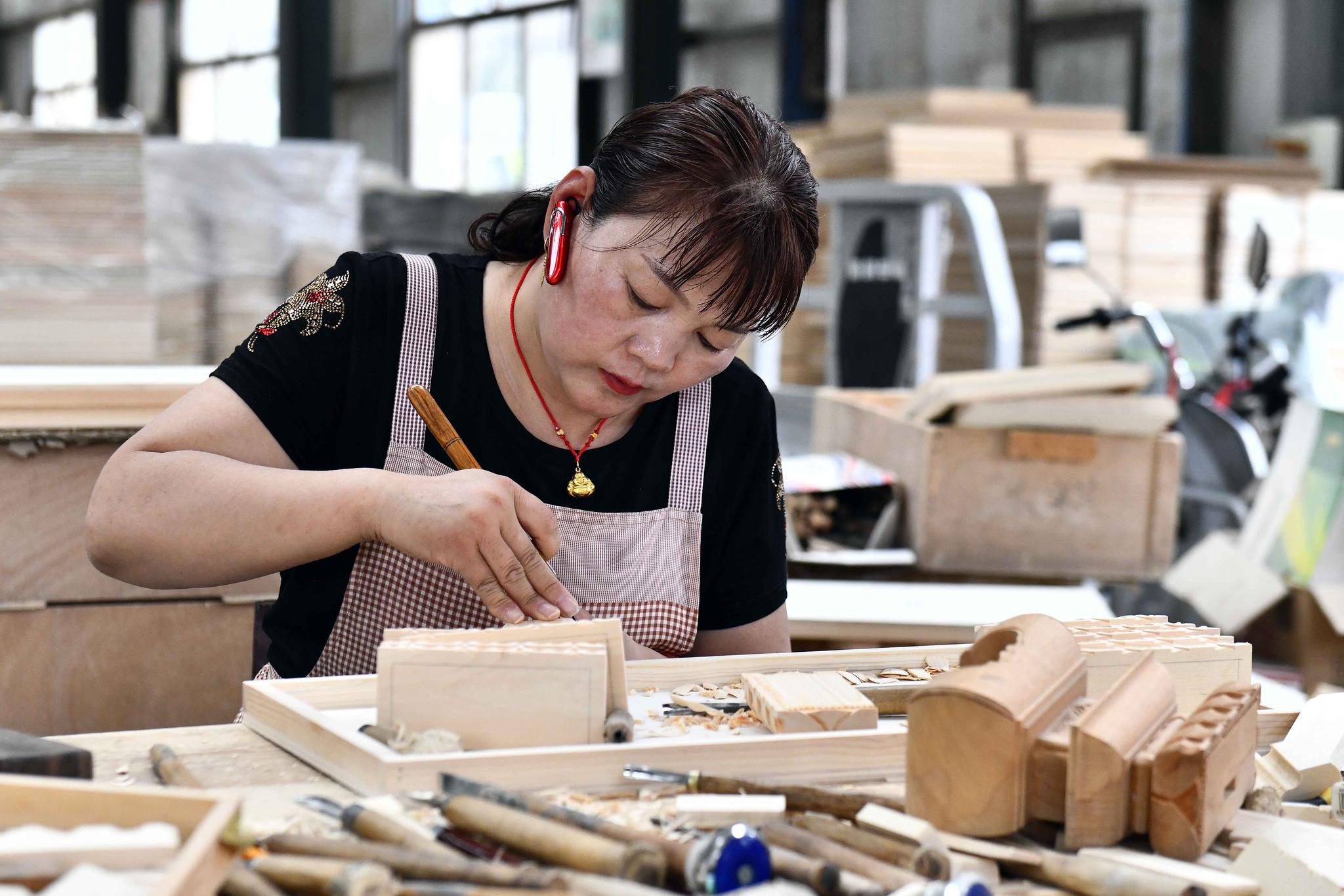 6月17日,在曹县云龙木雕工艺有限公司,工作人员在雕刻木制品.