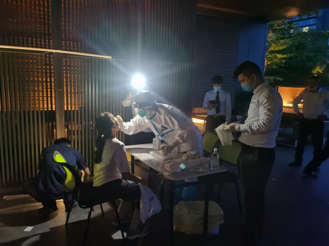 △ 暴雨来袭，核酸检测点搬到小区连廊，医护人员挑灯夜战。