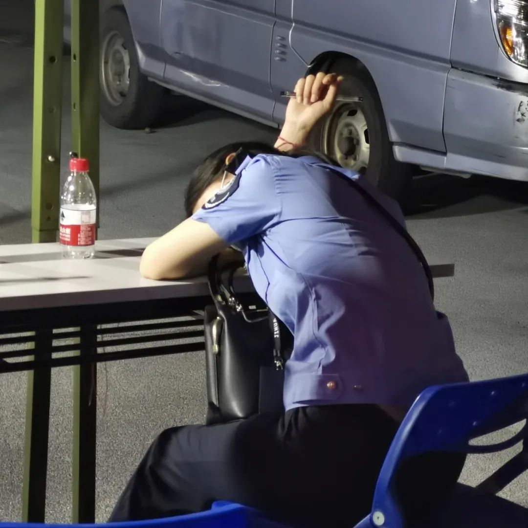 △ 深夜的核酸采样现场，一名疲惫不堪的网格员正在小憩。