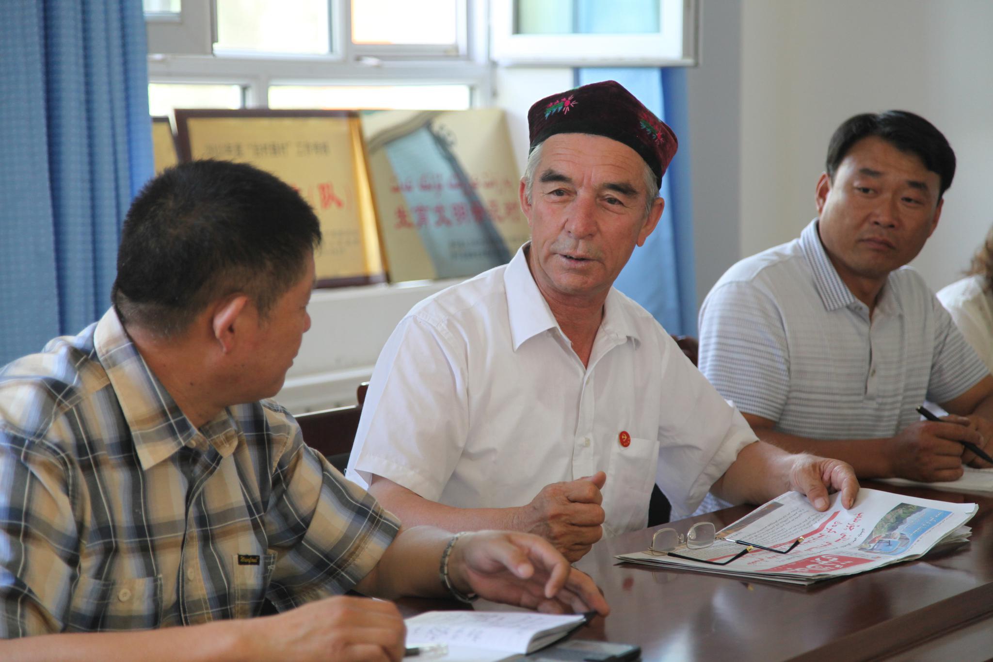买买提江·吾买尔(中)和村干部,村民们一同商量村里的事(2014年6月24