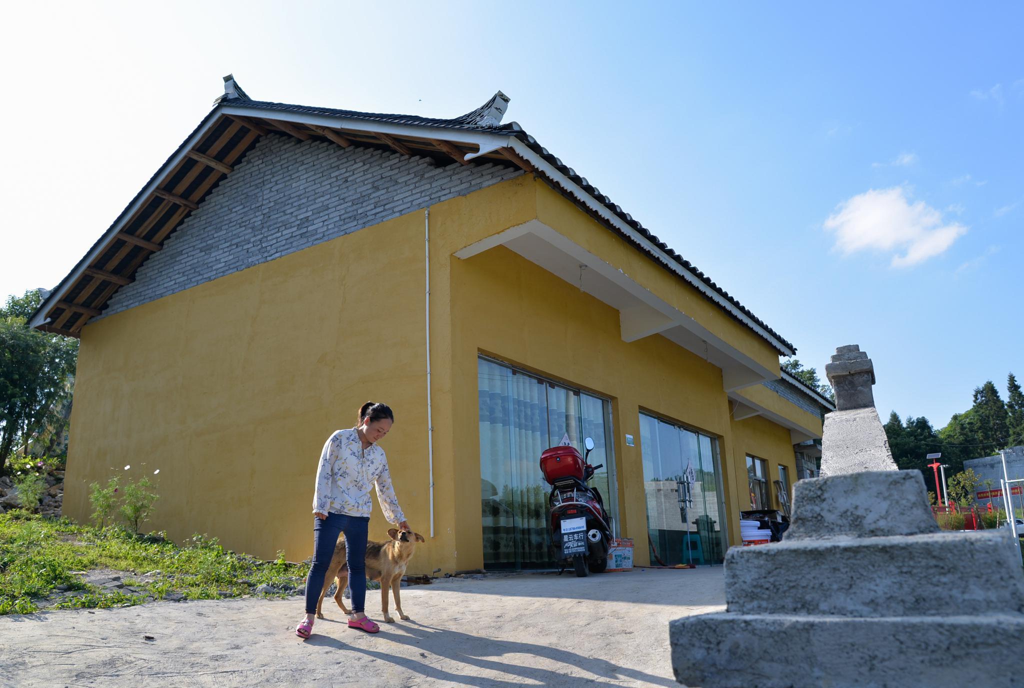 王婷婷在贵州省毕节市大方县凤山乡银川村自家新房前休息(7月14日摄)