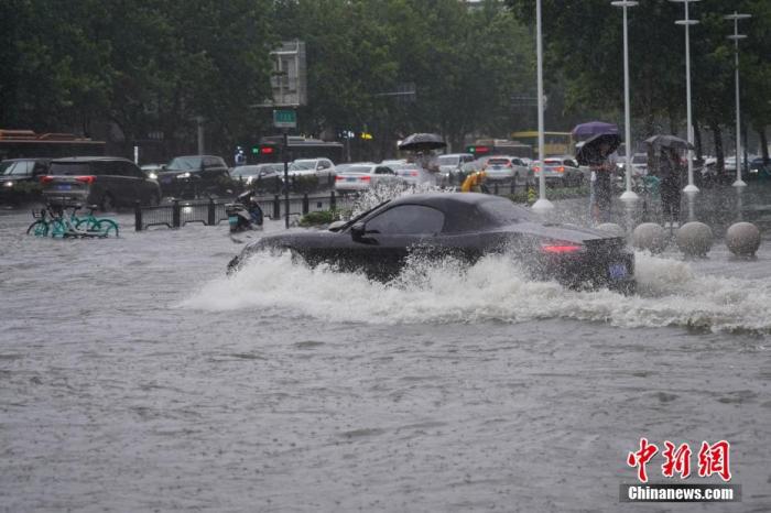 7月20日，河南郑州，车辆经过积水路段。近日，郑州连遭暴雨袭击，持续强降雨导致部分街道积水严重。 中新社记者 阚力 摄