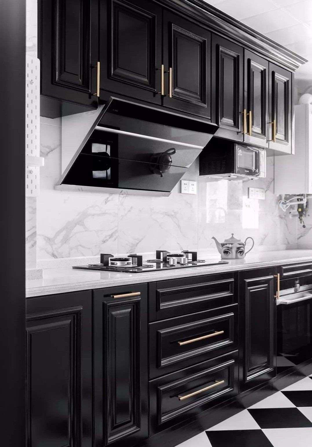 厨房选择了黑白简约的装修设计,用黑色的橱柜搭配白色的大理石台面