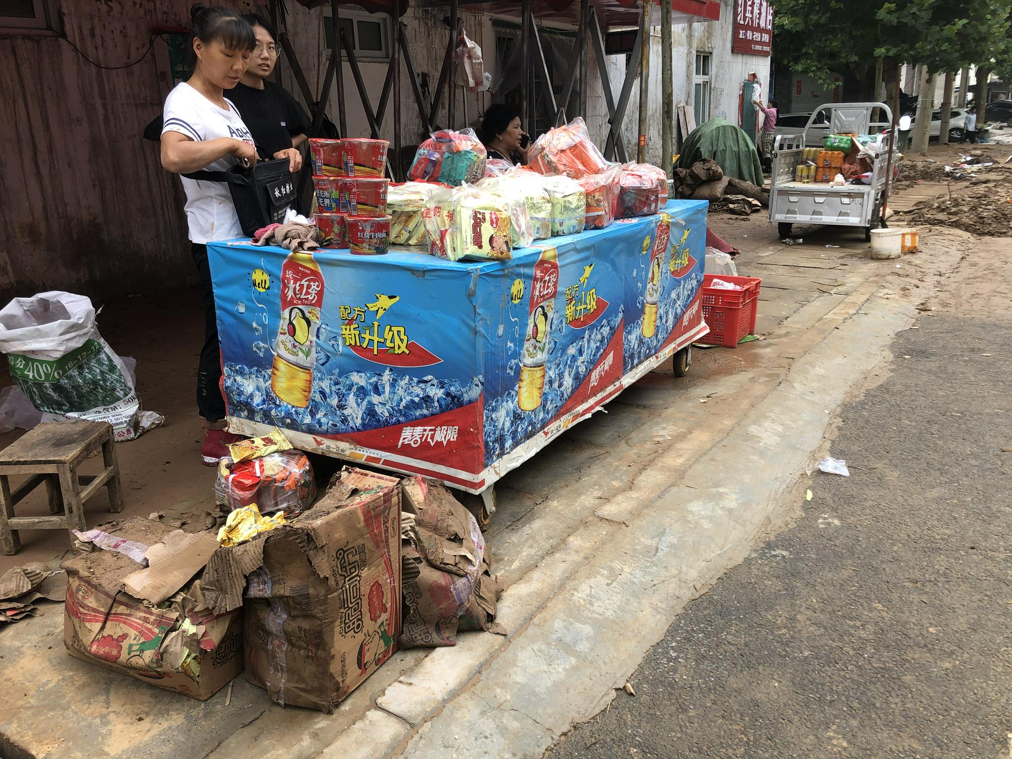 这家商店进水近一米深，许多商品被泡。图为商店主人将被水泡烂包装箱的方便面用塑料袋装起来售卖。