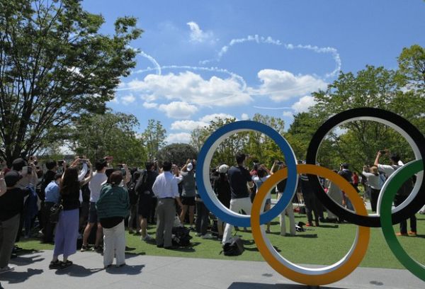 日本飞行表演队“蓝色冲击波”将在开幕式当天表演。图为7月21日的彩排中，人们在围观“蓝色冲击波”用彩烟在天空画出的奥运标志。（日本《每日新闻》网站）