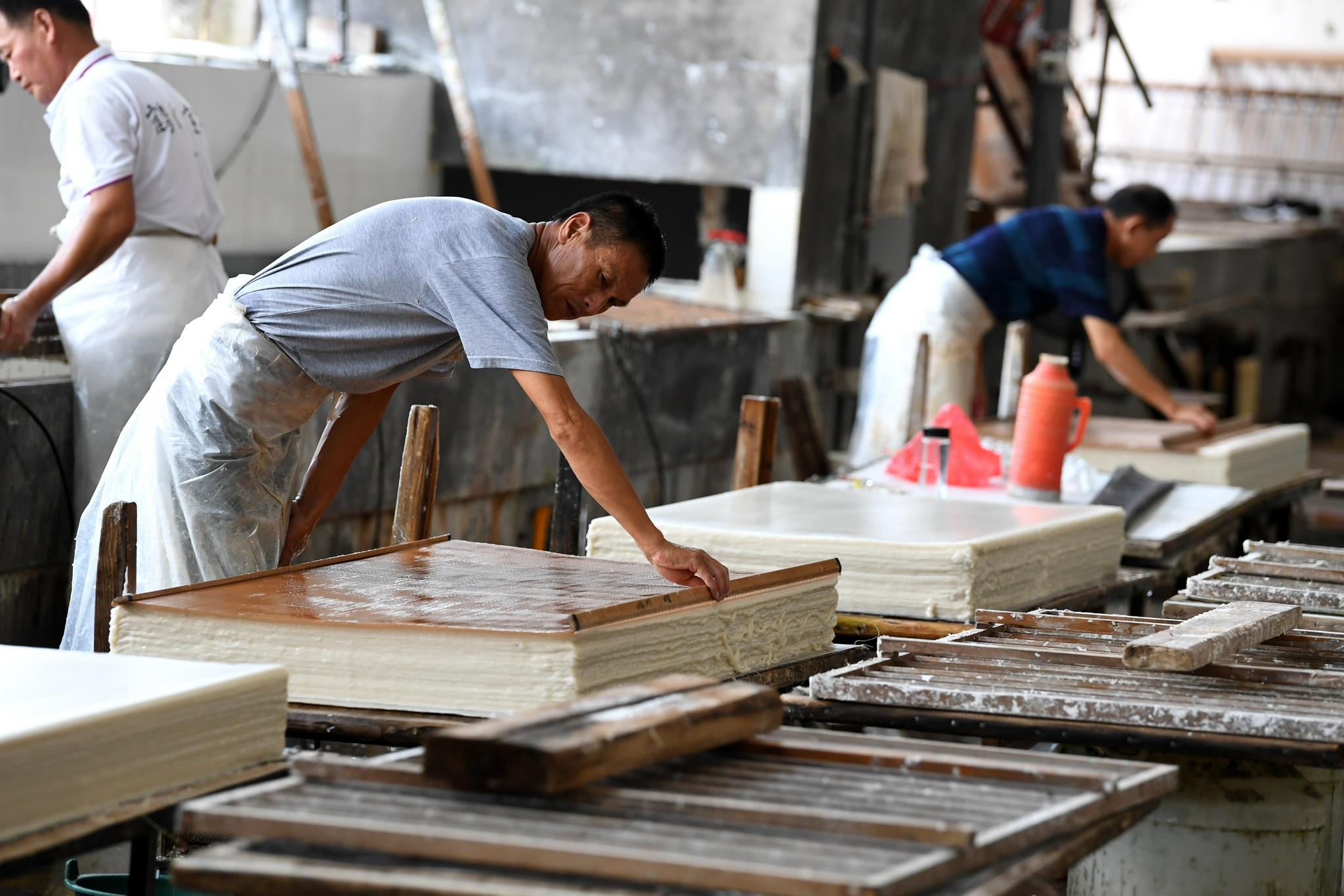 7月21日,在泾县丁家桥镇一家宣纸企业,工人在进行捞纸作业.