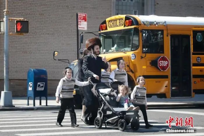 当地时间5月17日，民众从美国纽约市犹太社区的一所学校外经过。中新社记者 廖攀 摄